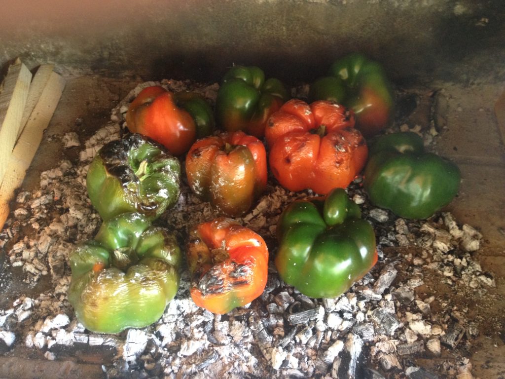 Peppers being cooked over wood embers
