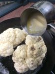 Pouring the butter over the cauliflower resting on our grill plan